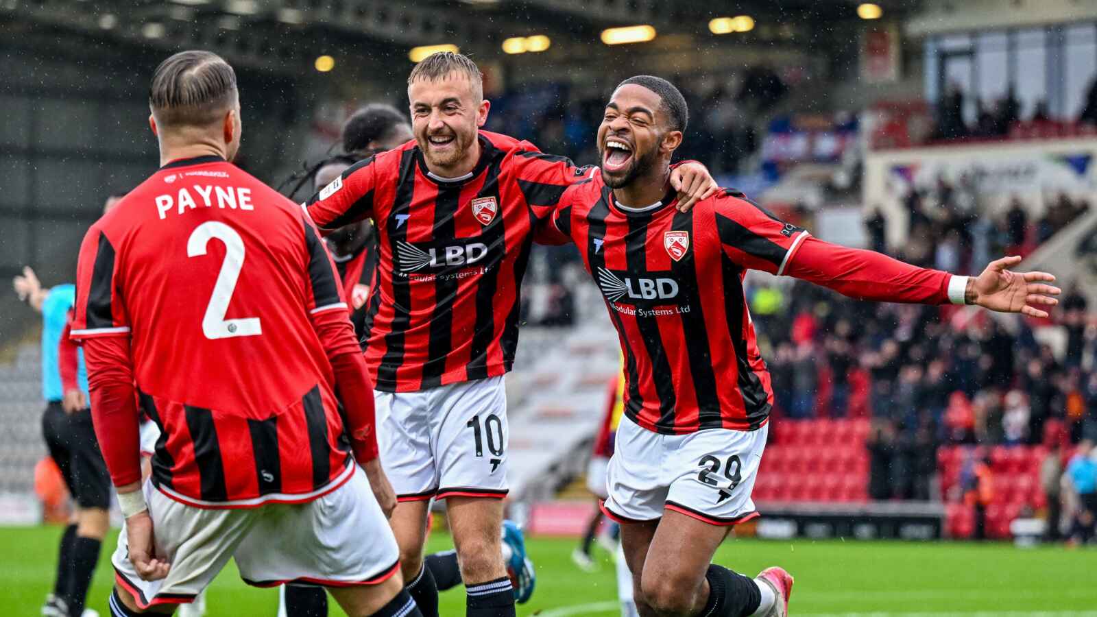 Elijah Dixon-Bonner celebrates with his Morecambe team-mates after finding the net in their seven-goal thriller against Wealdstone
