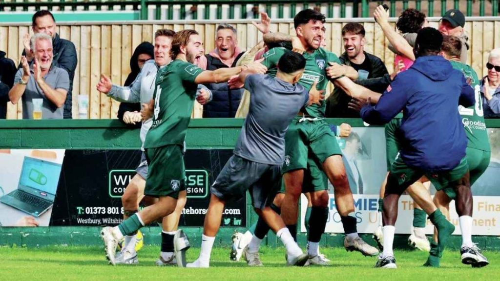 Match winner Ali Sen is mobbed as Westbury United celebrate a famous FA Cup triumph