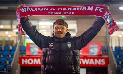 New Walton & Hersham manager Jakub Pietrzak holds aloft a Swans scarf