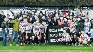 West Didsbury & Chorlton players celebrate with fans after beating Rossington Main in the last round