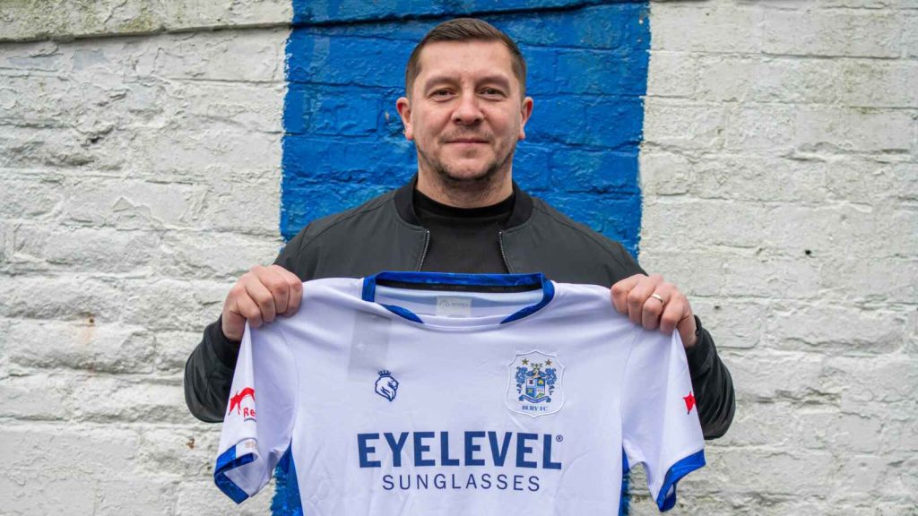 Bury&rsquo;s new boss Anthony Johnson proudly holds up the club shirt on his first day in charge at Gigg Lane.