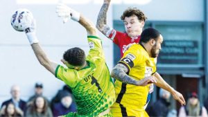 Chesham keeper Ben Goode and Dorking’s Alfie Rutherford meet mid air and, below, Dorking’s Kai Enslin makes advances in the midfield