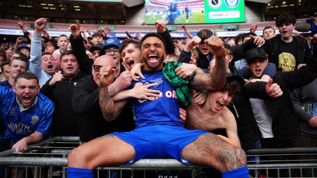 Tobi Adebayo-Rowling celebrates with the Rochdale fans after Dale sealed a dramatic return to the EFL at Wembley