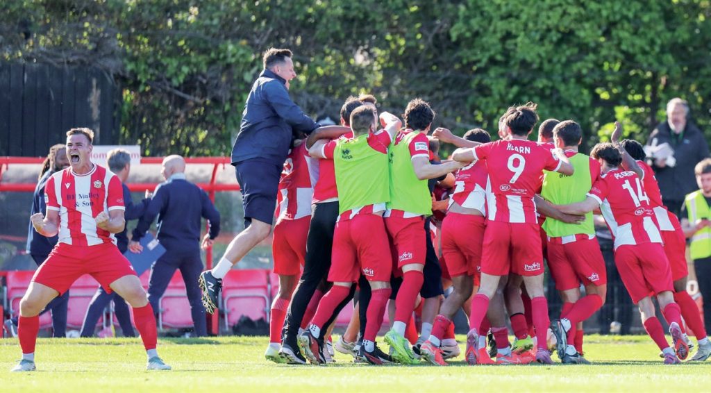 Hornchurch’s players surround goal hero Sam Ling in delight after his 117th-minute winner won his side promotion