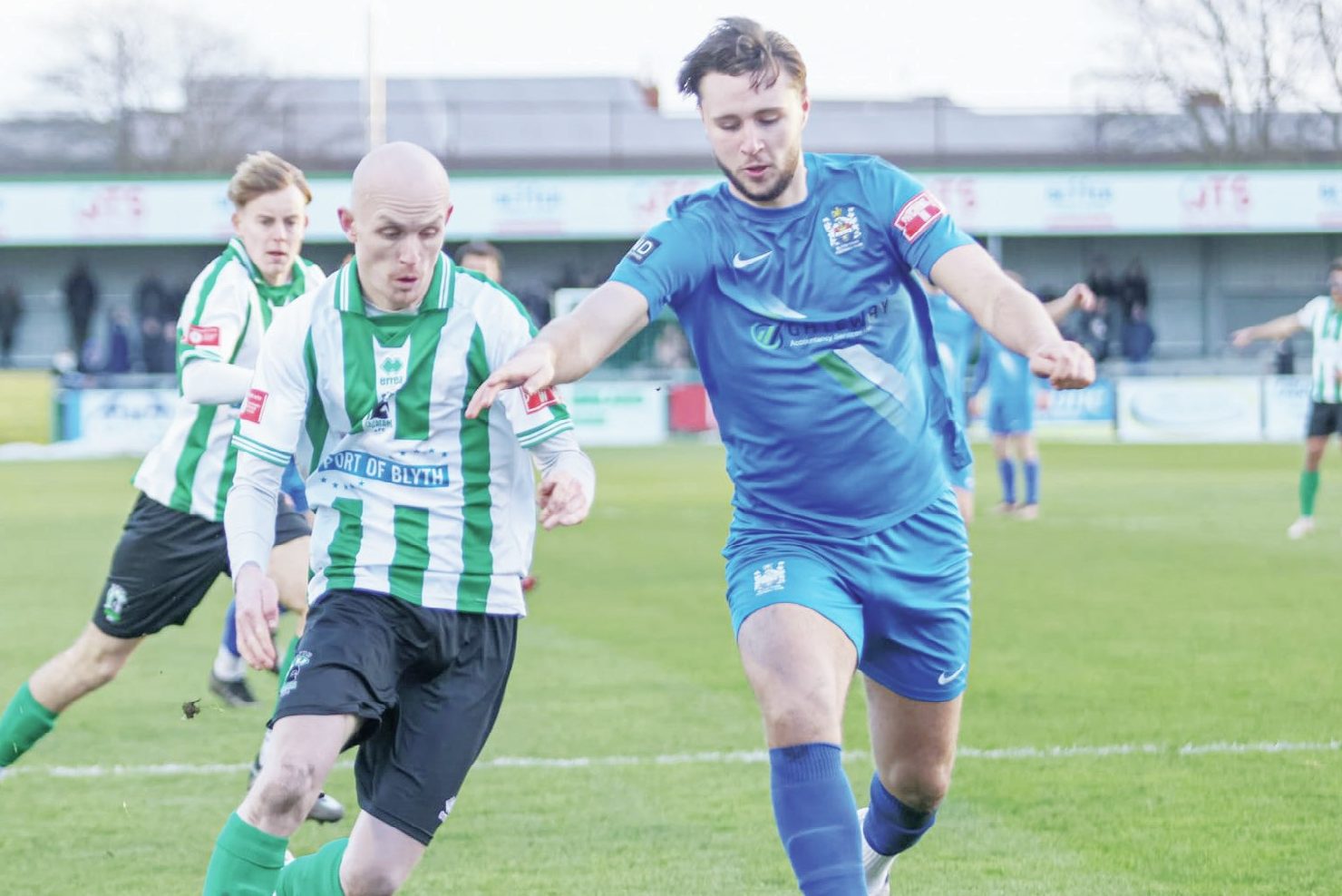 Blyth Town’s Ben Fell, in blue, son of manager Gavin, challenges Blyth Spartans’ Jack Foalle in the historic derby